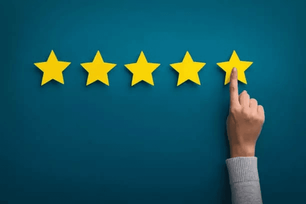 Five yellow review stars with a hand pressing the final star