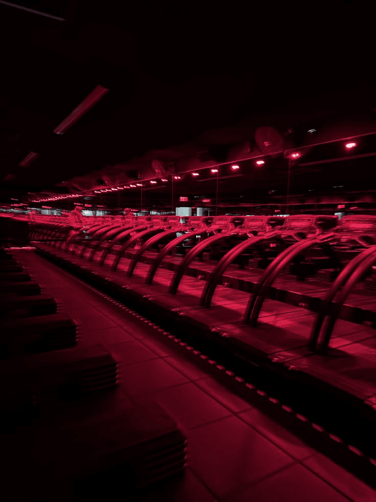 Red-lit boutique fitness studio treadmills before a class