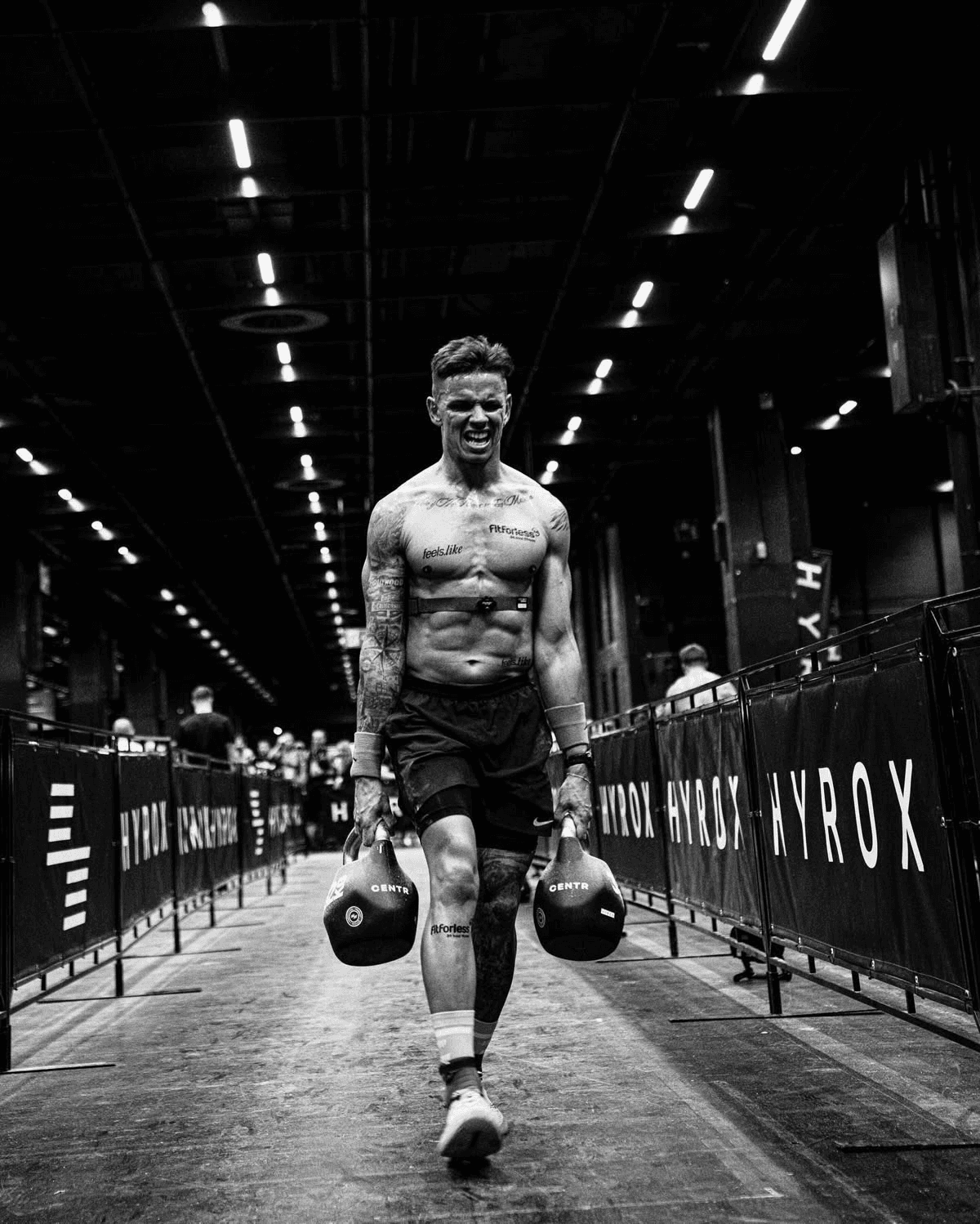 HYROX athlete carrying kettlebells during a race event